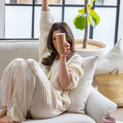 Woman on her couch in a well lit living room holding Moon Balance